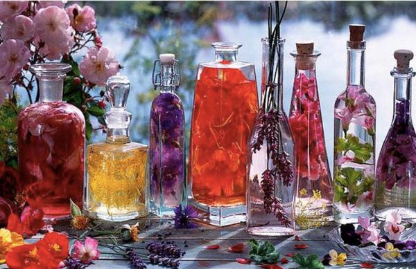 Különböző színű rózsákból rózsaecet többféle átlátszó üvegben.