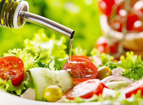 Friss zöldségekből készült salátára öntenek olívaolajat.