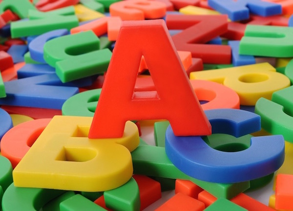 Színes műanyag játékbetűk tetején egy nagy piros A betű, mely egy kék B és egy sárga C betűn áll.