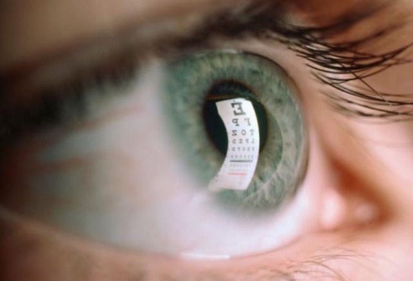Zöldes emberi szemben visszatükröződik a látásvizsgálat olvasási táblája.