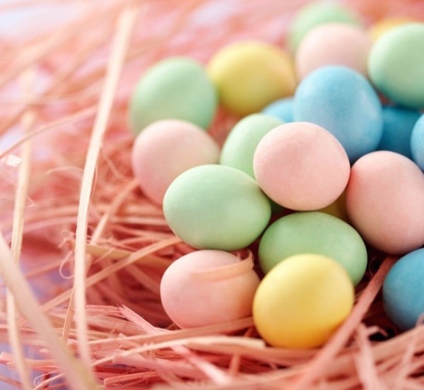 Gyógynövényekkel festett színes húsvéti tojások pasztellszínben pompázva egy fészekbe rakva.