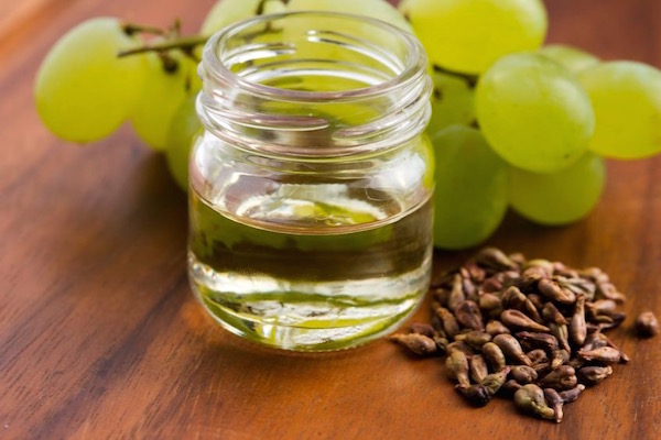 Fehér szőlő, szőlőmagok és kis üvegben zöldes színű szőlőmagolaj.
