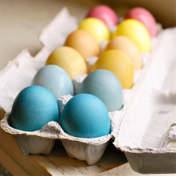 Természetes módon megfestett húsvéti tojások szép pasztellszínekben egy tojástartóba téve.