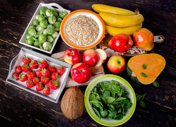 Magas rosttartalommal rendelkező élelmiszerek egymás mellett: banán, alma, eper, kelbimbó, kókuszdió, spenót, gabonapehely, sütőtök.