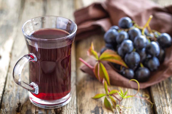 Egy fürt szőlő, mellette az egészséges szőlőlé üvegpohárban.