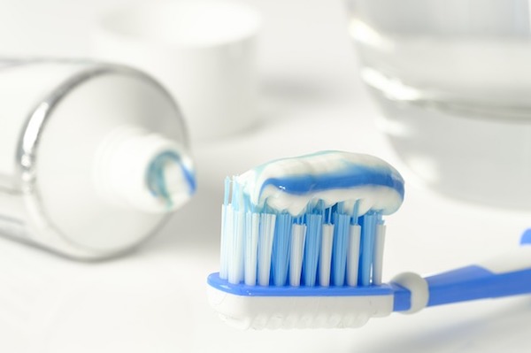 Kék és fehér színű fogkefén kék-fehér csíkozású fogkrém.