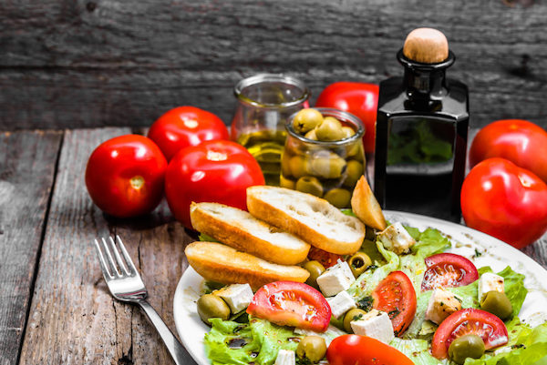 Tipikus mediterrán étel az asztalon: saláta, paradicsom, sajt, olívabogyó, olívaolaj.