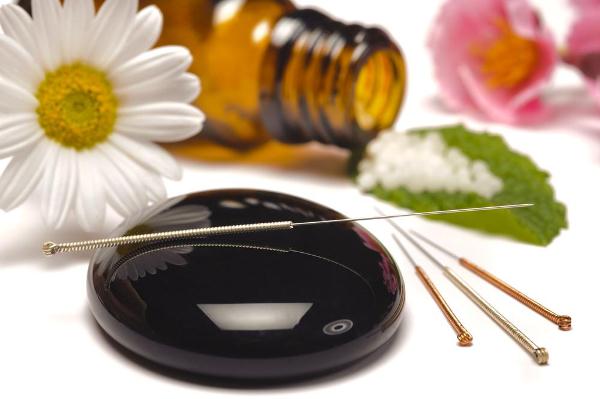 Alternatív gyógyászat eszközei: akupunktúrás tűk, homeopátiás golyók, virágok.