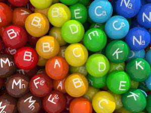 Színes cukorkákhoz hasonlító golyók, feliratozva a vitaminok és az ásványi anyagok jeleivel.