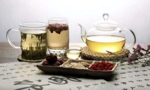 Kínai gyógynövényekből készült teák különféle poharakban, a terítőn kínai írásjelek.