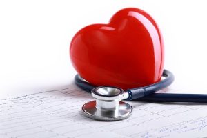 Piros műanyag szív, körülötte fonendoszkóp, alatta EKG-s görbe.