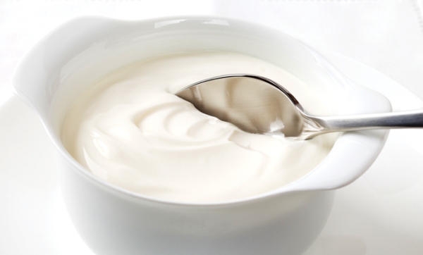 Porcelán tálkában probiotikumot tartalmazó joghurt, benne kiskanál.