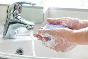 Lila színű szappannal mosnak kezet folyó víz alatt.