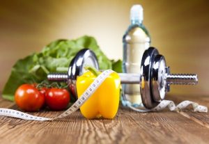 Egészséges életmód eszközei: zöldségek, súlyzó, ásványvíz és a diétára utaló centiméter.
