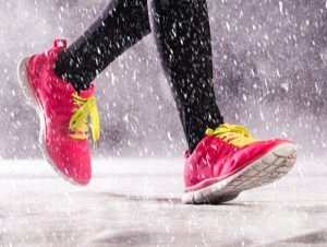 Hóesésben egy futó lába, rajta fekete futónadrág és pink színű sportcipő citromsárga fűzővel.