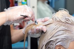Szőkére festik egy hölgy haját egy fodrászszalonban.