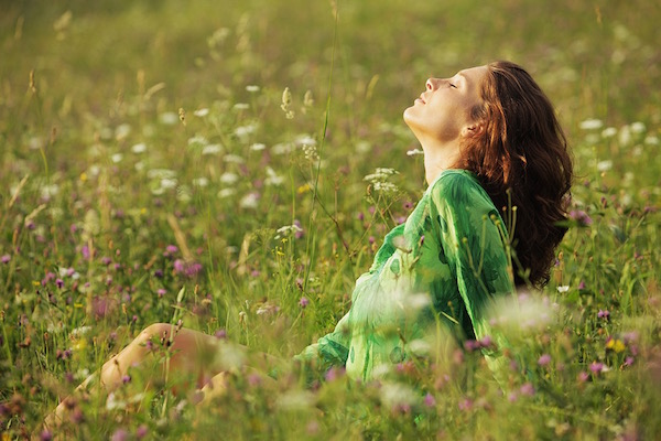 Vadvirágokkal teli réten ül a fűben egy vörös hajú lány, közben a napfénybe néz becsukott szemmel, és mélyeket lélegez.