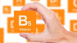 B5-vitamint ábrázoló narancssárga táblát tart egy női kéz.