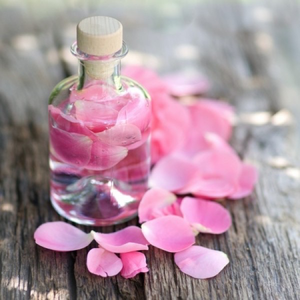 Rózsaszirmok és a belőlük készített rózsavíz csinos üvegcsében.