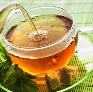 Gyógynövényből készült tea nőknek üvegcsészében barna cukorral.