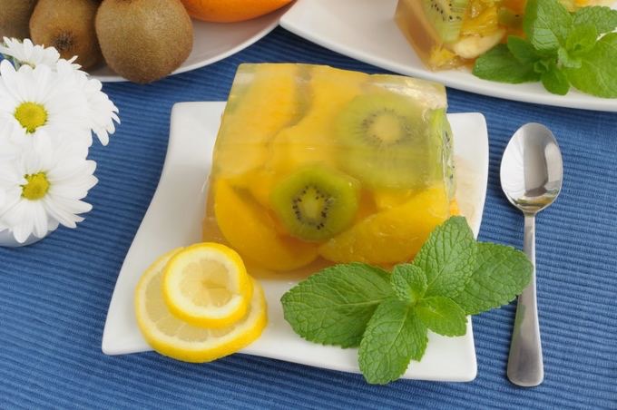 Kivis citromzselé egy kistányérra téve, mellette citromkarikák és citromfűlevélkék.