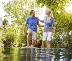 Víztaposást végez egy 50 év körüli házaspár egy hideg vízű patakban, amely lábszárközépig ér.