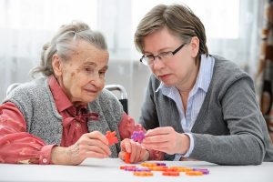 Idős, demens nénivel egyszerű puzzle-t játszik a lánya.