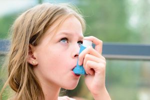 Kislány szájában kék színű spray asztma ellen.