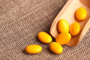 Sárga színű B-vitamint tartalmazó étrend-kiegészítők egy kis adagolóból kiöntve.