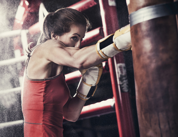 Fiatal nő bokszzsákos edzést tart.