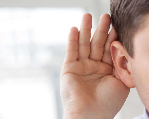 Középkorú férfi tenyerét füléhez emeli, hogy jobban halljon.