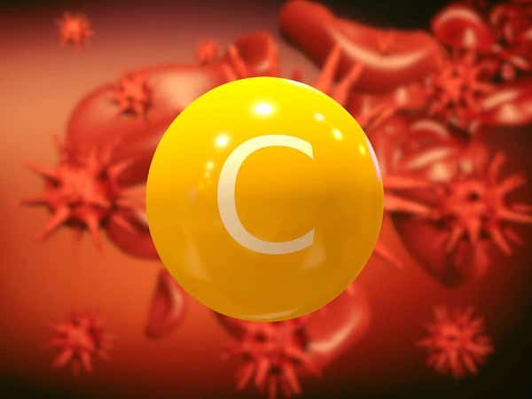Sárga golyó C betűvel (utalva a C-vitaminra), a háttérben daganatos sejtek.