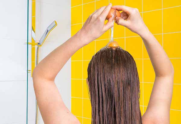 Tojást üt a hajára a zuhany alatt egy nő.