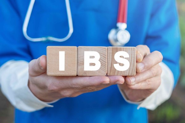 IBS betűi kockából kirakva, melyet egy orvos tart a kezében.