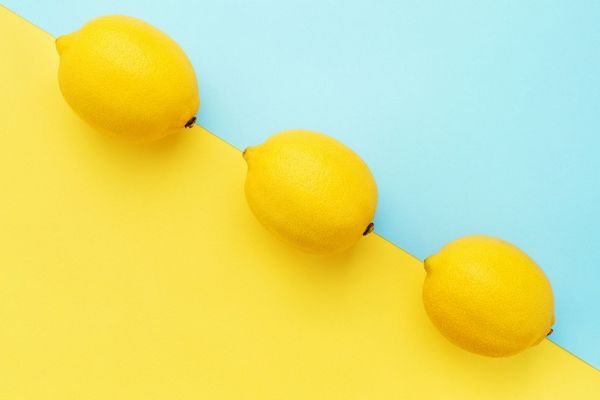 Egy sárga és világos kék háttéren három citrom látható.