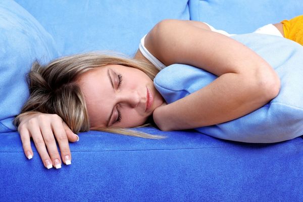 Egy kék ágyneműben fiatal nő alszik.