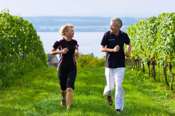 Egy középkorú házaspár edzőruhában a szőlős kertben egymásra mosolyogva fut.