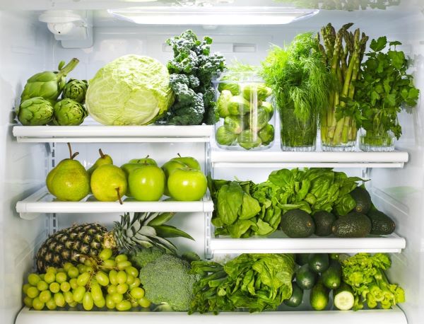 Hűtőbelső zöld színű zöldségekkel, gyümölcsökkel és fűszernövényekkel.