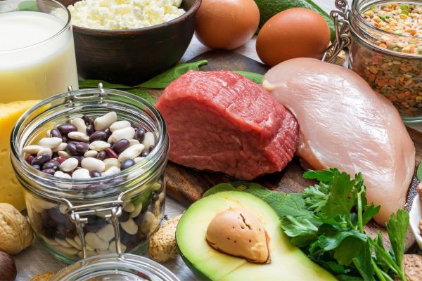 Asztalon B-vitamin-tartalmú élelmiszerek: marhahús, avokádó, bab, lencse, túró, tej, tojás, dió, pulykamell.