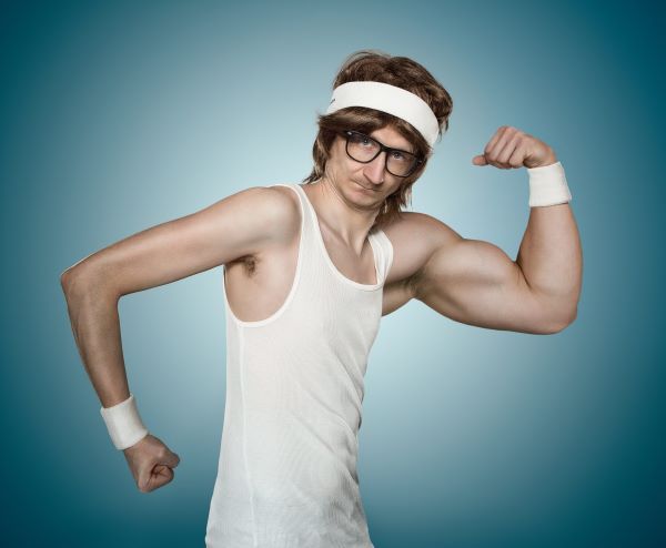 Vékony, szemüveges férfi fehér trikóban és fejpánttal, csuklószorítókkal, bal karján a bicepszet feszítve mutatja aránytalanul izmos mivoltát, míg jobb karja átlagon aluli izmosságú.