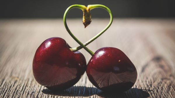 Faasztalon egy pár cseresznye, amelynek a szára szív alakban csavarodik.