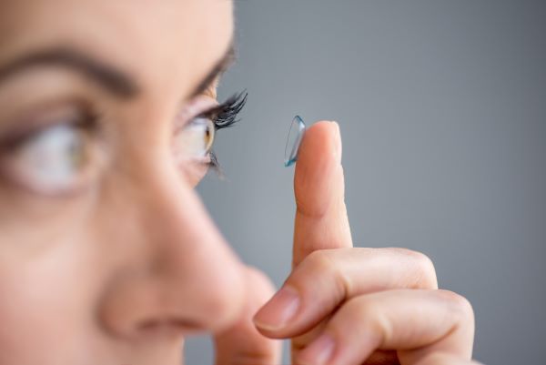 Nő bal szeme elé egy kontaktlencsét tart az ujjával.