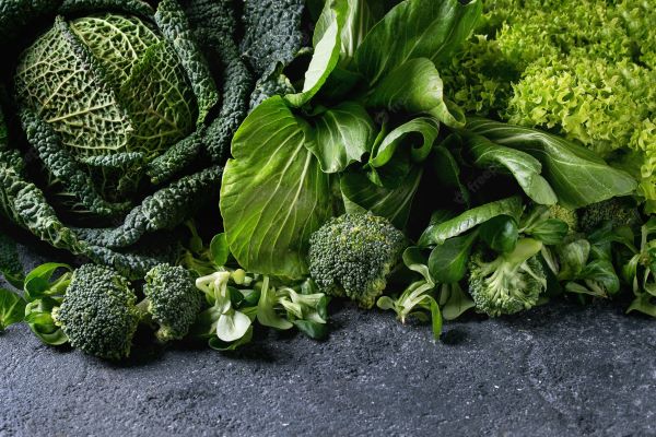 Egy kupac zöld leveles zöldség: káposzta, kelkáposzta, saláta, brokkoli.