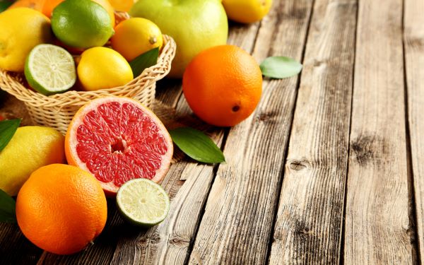 Faasztalon kis kosárban és mellette citrusfélék (grépfrút, narancs, lime, citrom) és egy alma.