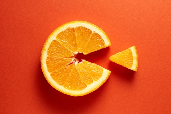 Narancssárga háttéren kerek narancsszelet, amelyből egy cikket kivágtak, így C betűhöz hasonlít.