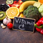 Gyümölcsök és zöldségek csoportja "Vitamin C" feliratú táblával.
