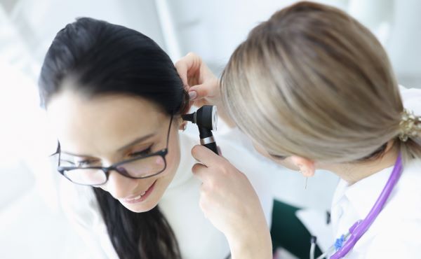 Doktornő vizsgálja női páciense fülét.
