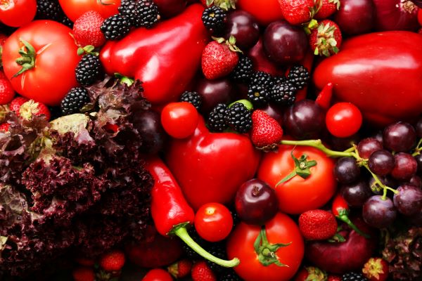 Piros zöldségek és gyümölcsök egy kupacban: paradicsom, paprika, szeder, eper, szőlő, saláta, meggy.