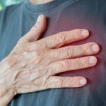 Idősebb férfi mellkasára teszi az egyik kezét.