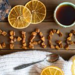 Asztalon chaga gombából kirakva a "chaga" szó, fölötte egy csésze kávé, szárított narancskarikák, alatta kiskanál.